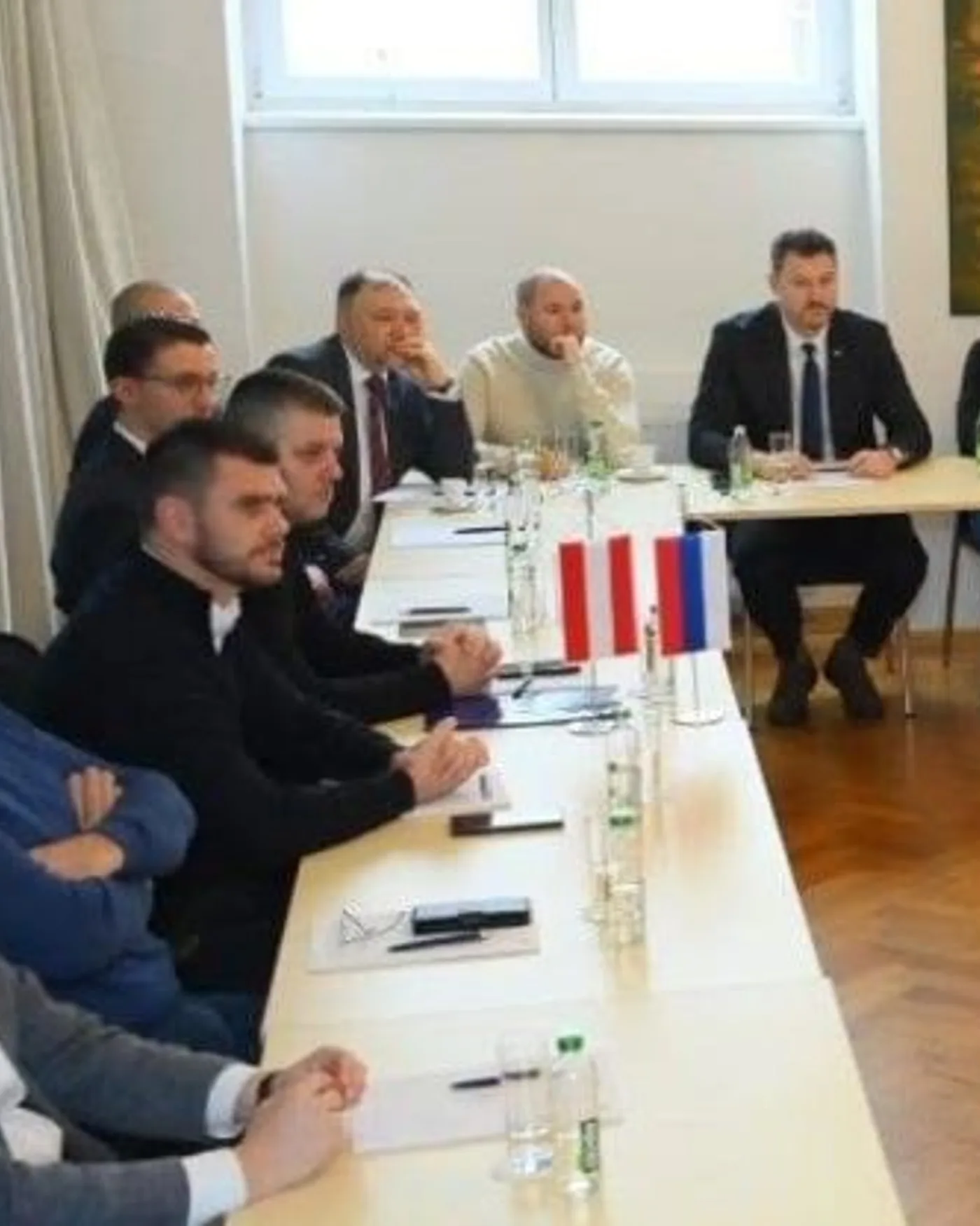 Runde an einer langen Tafel mit Tischfähnchen Österreichs und Serbiens